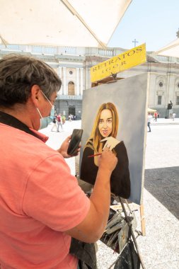 Santiago de Chile, Şili, 20-10-2019: Bir erkek bir kadın portresi yapıyor. Kadın siyah bir elbise giyiyor ve sarı saçlı. Resmin adı Retratos..