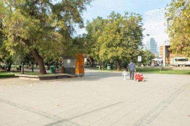 Santiago de Chile, Şili, 27-06-2021: Bir adam ve bir çocuk bir parkta kaldırımda yürüyorlar. Adam kırmızı bir oyuncak araba itiyor. Sahne huzurlu ve sakin..