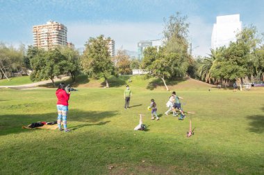 Santiago de Chile - Şili, 27-06-2021: Bir grup insan parkta frizbi oynuyor. Bir kadın grubun fotoğrafını çekiyor..