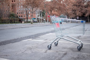 Santiago de Chile, Şili, 27-06-2021: Bir alışveriş arabası bir otoparkta duruyor. Araba boş ve kırmızı bir sapı var. Otopark boş ve gökyüzü bulutlu..