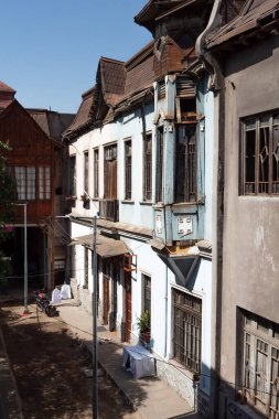 Santiago de Chile, Şili, 27-06-2021: Ortasında mavi olan bir sıra eski bina. Mavi binada bir balkon ve saksı bitkisi var..