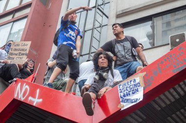 Santiago de Chile - Şili, 25-10-2019: Bir grup protestocu kırmızı bir köprüde, ellerinde işaretler ve maskeler var. Sahne gergin ve ciddi. Protestocular bir köprüde duruyor ve ellerinde işaretler var.