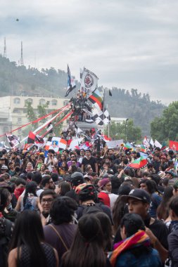 Santiago de Chile - Şili, 25-10-2019: Bir şehir meydanında çeşitli bayraklar taşıyan büyük bir kalabalık toplandı. Etkinliğe her yaştan insanın katıldığı atmosfer canlı ve enerjik.