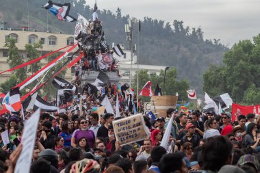 Santiago de Chile - Şili, 25-10-2019: Bir şehir meydanında büyük bir kalabalık toplandı, işaretler ve bayraklar taşıyorlar. Sahne, insanların fikirlerini ve desteklerini dile getirmek için bir araya geldiği protesto ve birliktir.