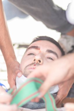 Santiago de Chile - Şili, 25-11-2019: Biri yeşil bandajlı iki kişi tarafından yardım ediliyor. Adamın ağzı ve burnu bandajlı.