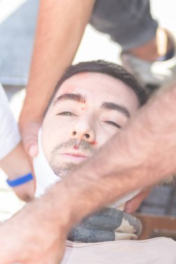 Santiago de Chile - Şili, 25-11-2019: Sargılı yüzlü bir adam diğer iki adam tarafından tutuluyor. Adamın yüzü bandajlı ve burnu kanıyor. Sahne gergin ve ciddi, çünkü adam baskı altında.