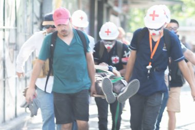 Santiago de Chile - Şili, 25-11-2019: Yeşil gömlekli bir adam sedye üzerinde bir adam taşıyor. Yeşil gömlekli adam kırmızı bir şapka giyiyor.