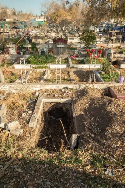 Santiago de Chile, Şili, 25-05-2021: Yerde büyük bir delik olan bir mezarlık. Delik bir çitle çevrili ve toprakla dolu. Mezarlıkta birkaç mezar var..