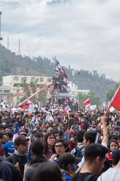 Santiago de Chile - Şili, 25-10-2019: Büyük bir kalabalık, bazıları kırmızı, beyaz ve mavi olmak üzere bayraklar ve pankartlar kaldırıyor. Etkinliğe her yaştan insanın katıldığı atmosfer canlı ve enerjik.