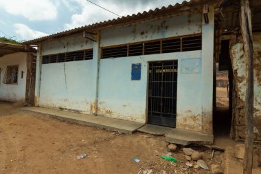 Üzerinde mavi tabela olan bir bina. Bina eski ve çok hasar görmüş.