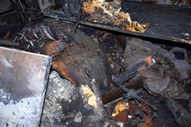 Yangın, arkasında bir yığın enkaz ve yanmış eşya bırakarak bir evi yok etti. Havayı kaplayan duman ve kül kokusuyla sahne kaotik ve bunaltıcı.