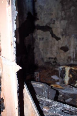 Yanmış duvarı ve yanmış yatağı olan karanlık bir oda. Oda kargaşa ve yıkım içinde.