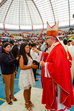 Tumbes, Tumbes, Peru 21-10-2023, Doğrulama Ayini: Kırmızı cüppeli bir adam bir kızı kutsuyor. Kız beyaz bir elbise giyiyor.