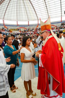 Tumbes, Tumbes, Peru 21-10-2023, Doğrulama Ayini: Kırmızı cüppeli bir adam beyaz elbiseli bir kadınla konuşuyor. Kadın diz çöküyor ve adam ayakta duruyor. Sahne dini bir tören ya da etkinlik gibi görünüyor.