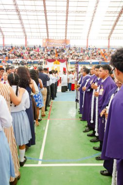 Tumbes, Tumbes, Peru 21-10-2023, Onaylama Ayini: Bir grup insan stadyumda sıralanmış, bazıları mor cübbe giyiyor. Atmosfer muhtemelen bir kutlama ya da törendir.