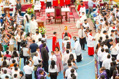 Tumbes, Tumbes, Peru 21-10-2023, Onaylama Ayini: Bir odada toplanan büyük bir kalabalık, ortasında bir rahip duruyor. Rahibin etrafı, bazıları el ele tutuşan insanlarla çevrili. Atmosfer neşeli görünüyor.