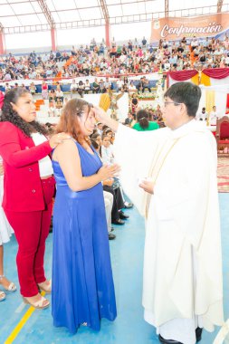 Tumbes, Tumbes, Peru 21-10-2023, Doğrulama Ayini: Bir kadın bir rahip tarafından dokunuluyor. Rahip beyaz bir bornoz giyiyor. Kadın mavi bir elbise giyiyor.