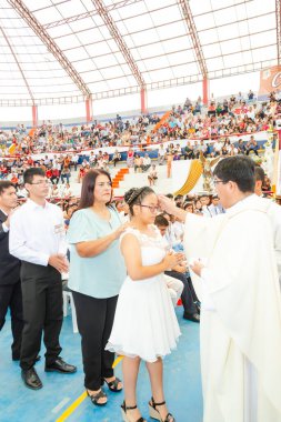 Bir rahip beyaz elbiseli genç bir kızı kutsuyor. Kız rahip tarafından kutsandı.