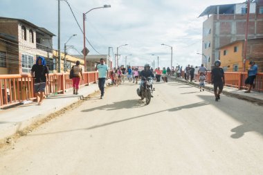 Tumbes, Tumbes, Peru 01-03-2025: Motosikletli bir adam arkasında bir grup insanla caddede yürüyor. Sahne hareketli ve hareketli, her yaştan insan ve arka planda geziniyor.