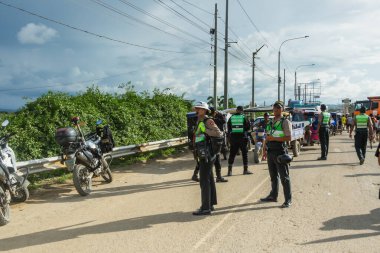 Tumbes, Tumbes, Peru 01-03-2025: Bir grup polis memuru bir motosikletin yanında sokakta duruyor. Subaylar yeşil üniforma giyiyorlar ve bir şeye bakıyorlar.