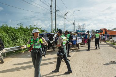 Tumbes, Tumbes, Peru 01-03-2025: Bir grup polis memuru arka planda bir kamyonla yolda yürüyor. Olay yeri gergin ve ciddi. Memurların ilgilenmesi gereken bir durumla karşı karşıya olması muhtemel.