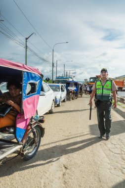 Tumbes, Tumbes, Peru 01-03-2025: Yeşil yelekli bir adam bir grup insanla sokakta yürüyor. Bu adam bir polis memuru.