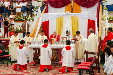 Tumbes, Tumbes, Peru 21-10-2023, Onaylama Ayini: Bir grup rahip ortada bir rahiple bir masada diz çöküyor. Ortadaki rahip elinde bir şarap kadehi tutuyor. Rahipler kırmızı cübbe giyiyor.