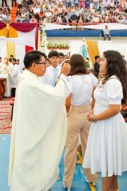 Tumbes, Tumbes, Peru 21-10-2023, Onaylama Ayini: Bir rahip beyaz elbiseli genç bir kadını kutsar. Kadın beyaz bir elbise giyiyor ve rahip tarafından kutsanmış.
