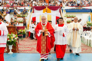 Tumbes, Tumbes, Peru 21-10-2023, Onaylama Ayini: Bir grup rahip elinde altın haç tutan bir adamla kırmızı halıda yürüyorlar. Kalabalık geçidi izliyor.