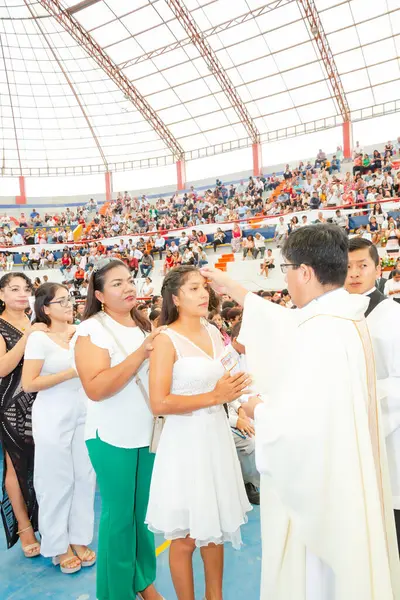 Tumbes, Tumbes, Peru 21-10-2023, Onaylama Ayini: Bir rahip beyaz elbiseli genç bir kadını kutsar. Kadının etrafı bir grup insanla çevrili, bazıları beyaz giyiyor. Atmosfer neşeli ve kutlama dolu.