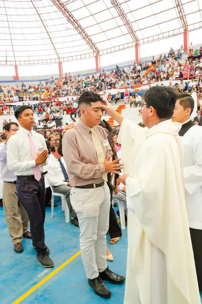 Tumbes, Tumbes, Peru 21-10-2023, Onaylama Ayini: Bir adam kalabalığın önünde bir rahip tarafından kutsanmaktadır. Rahip beyaz bir bornoz giyiyor ve kutsanan adam gri bir gömlek giyiyor.