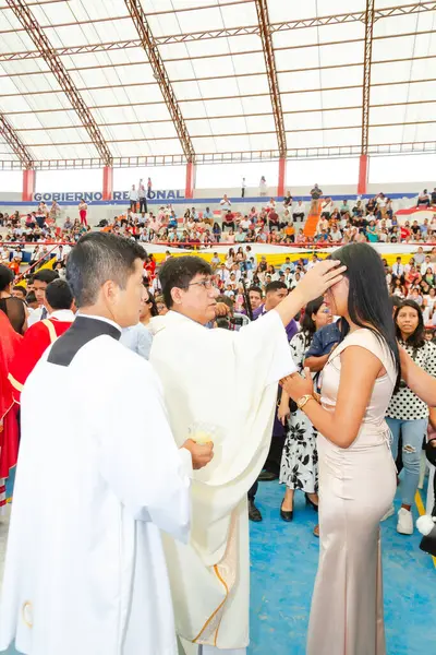 Tumbes, Tumbes, Peru 21-10-2023, Doğrulama Ayini: Beyaz cüppeli bir adam bir kadının kafasına dokunuyor. Kadın elbise giyiyor ve etrafını bir sürü insan sarmış.