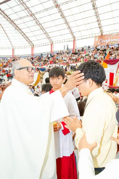 Tumbes, Tumbes, Peru 21-10-2023, Onaylama Ayini: Bir rahip genç bir adamı beyaz cüppeyle kutsar. Rahip beyaz bir cübbe ve gözlük takıyor.