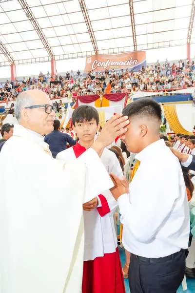 Tumbes, Tumbes, Peru 21-10-2023, Onaylama Ayini: bir rahip genç bir adamı eliyle kutsar. Genç adam beyaz bir gömlek giyiyor.