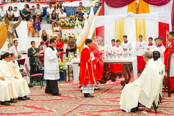 Tumbes, Tumbes, Peru 21-10-2023, Onaylama Ayini: Bir grup kırmızı cüppeli adam bir rahiple birlikte masanın etrafında toplandı. Papaz elinde beyaz bir mum tutuyor ve adamlar bakıyor. Sahne kutsal ve dindardır.