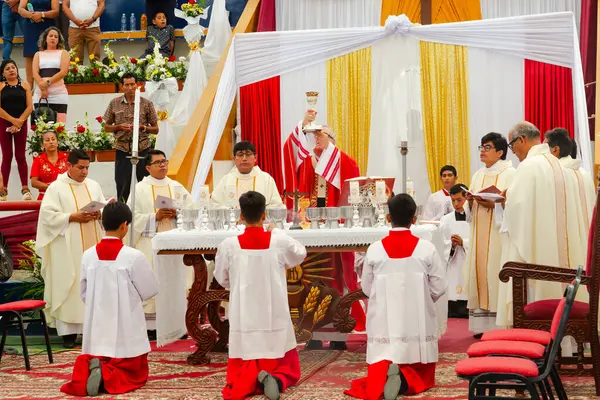 Tumbes, Tumbes, Peru 21-10-2023, Doğrulama Ayini: Kırmızı ve beyaz cüppeli bir grup adam beyaz bir bezle bir masanın önünde diz çöküyor. Adamlardan biri beyaz bir nesne tutuyor. Sahne dini bir tören ya da toplantı gibi görünüyor.