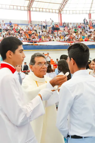 Tumbes, Tumbes, Peru 21-10-2023, Onaylama Ayini: Bir rahip genç bir adama bir parça ekmek veriyor. Rahip beyaz bir bornoz giyiyor ve genç adam beyaz bir gömlek giyiyor.