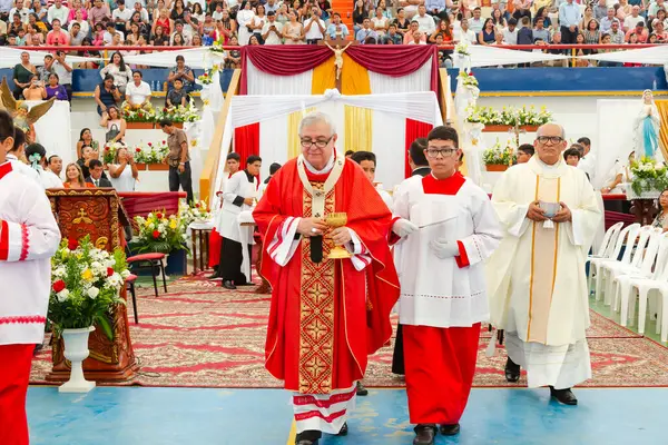 Tumbes, Tumbes, Peru 21-10-2023, Onaylama Ayini: Bir grup rahip elinde altın haç tutan bir adamla kırmızı halıda yürüyorlar. Kalabalık geçidi izliyor.