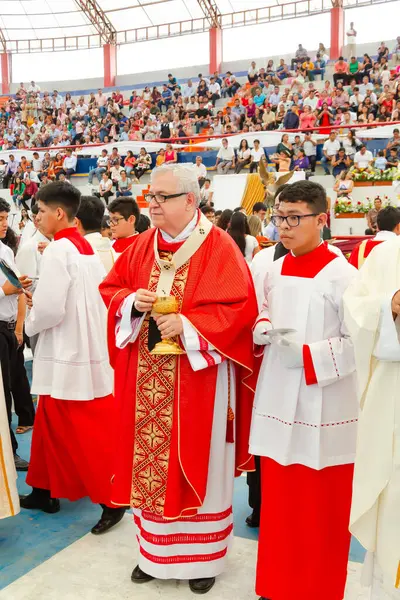 Tumbes, Tumbes, Peru 21-10-2023, Ayin Ayini: Bir grup rahip stadyumda onları izleyen bir kalabalıkla birlikte duruyor. Rahipler kırmızı cübbe giyiyor ve içlerinden biri küçük bir nesne tutuyor.