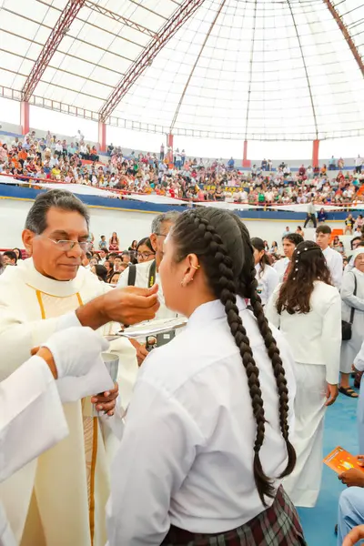 Tumbes, Tumbes, Peru 21-10-2023, Doğrulama Ayini: Bir adam kalabalıkta bir kadını besliyor. Kalabalık etkinliği izliyor. Adam beyaz bir bornoz giyiyor ve kadın beyaz bir gömlek giyiyor.