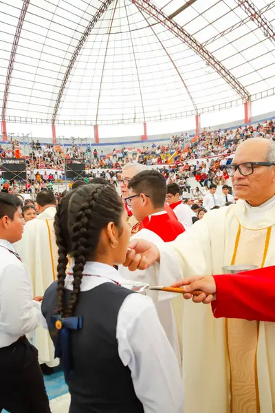 Tumbes, Tumbes, Peru 21-10-2023, Doğrulama Ayini: Bir rahip genç bir kızı kutsuyor. Rahip kırmızı bir bornoz giyiyor ve kız beyaz bir gömlek giyiyor. Papazın elinde tahta bir sopa, kızın elinde de bir bardak var.