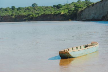 Küçük bir tekne nehirde yüzüyor. Su kahverengi ve bulanık. Sahnede görünen tek şey tekne.