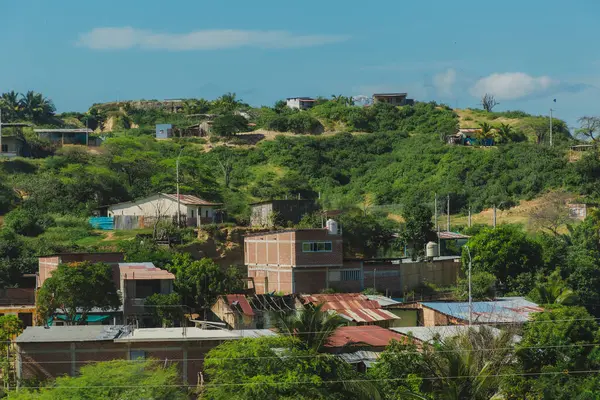 Evlerin ve arka planda tepenin olduğu bir kırsal alan. Evler küçük ve tuğladan yapılma.