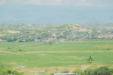 Uzakta küçük bir kasaba olan geniş, açık bir alan. Gökyüzü bulutlu ve atmosfer huzurlu.