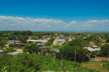 Bir sürü evi ve ağacı olan küçük bir kasaba. Gökyüzü mavi ve bazı bulutlar var.