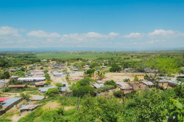 Bir sürü evi ve bir kaç ağacı olan küçük bir kasaba. Gökyüzü mavi ve bazı bulutlar var.