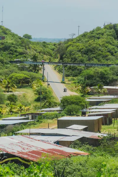 Toprak yolu ve birkaç evi olan bir kırsal bölge. Evler tenekeden yapılmış ve çatıları var.