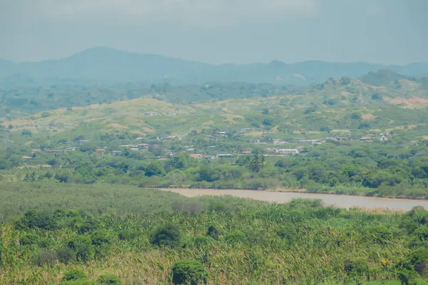 İçinden nehir akan yemyeşil bir vadi. Vadi dağlarla çevrili ve gökyüzü bulutlu.