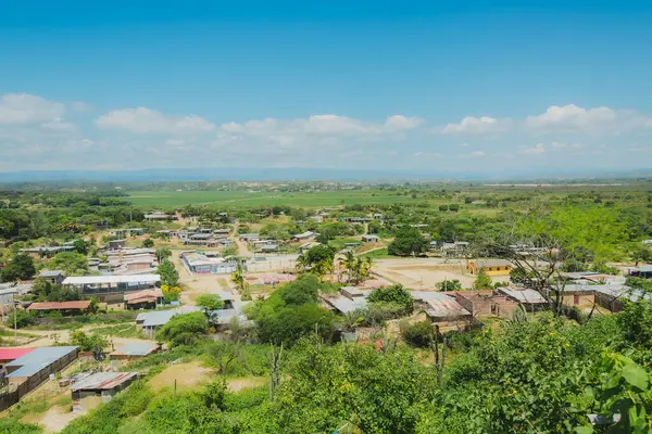 Bir sürü evi ve bir kaç ağacı olan küçük bir kasaba. Gökyüzü mavi ve bazı bulutlar var.