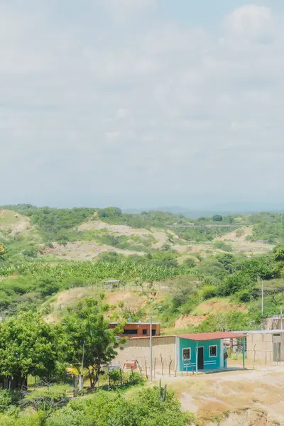 Küçük bir ev dağ manzaralı bir yamaç üzerindedir. Ev ağaçlarla çevrili ve gökyüzü temiz.